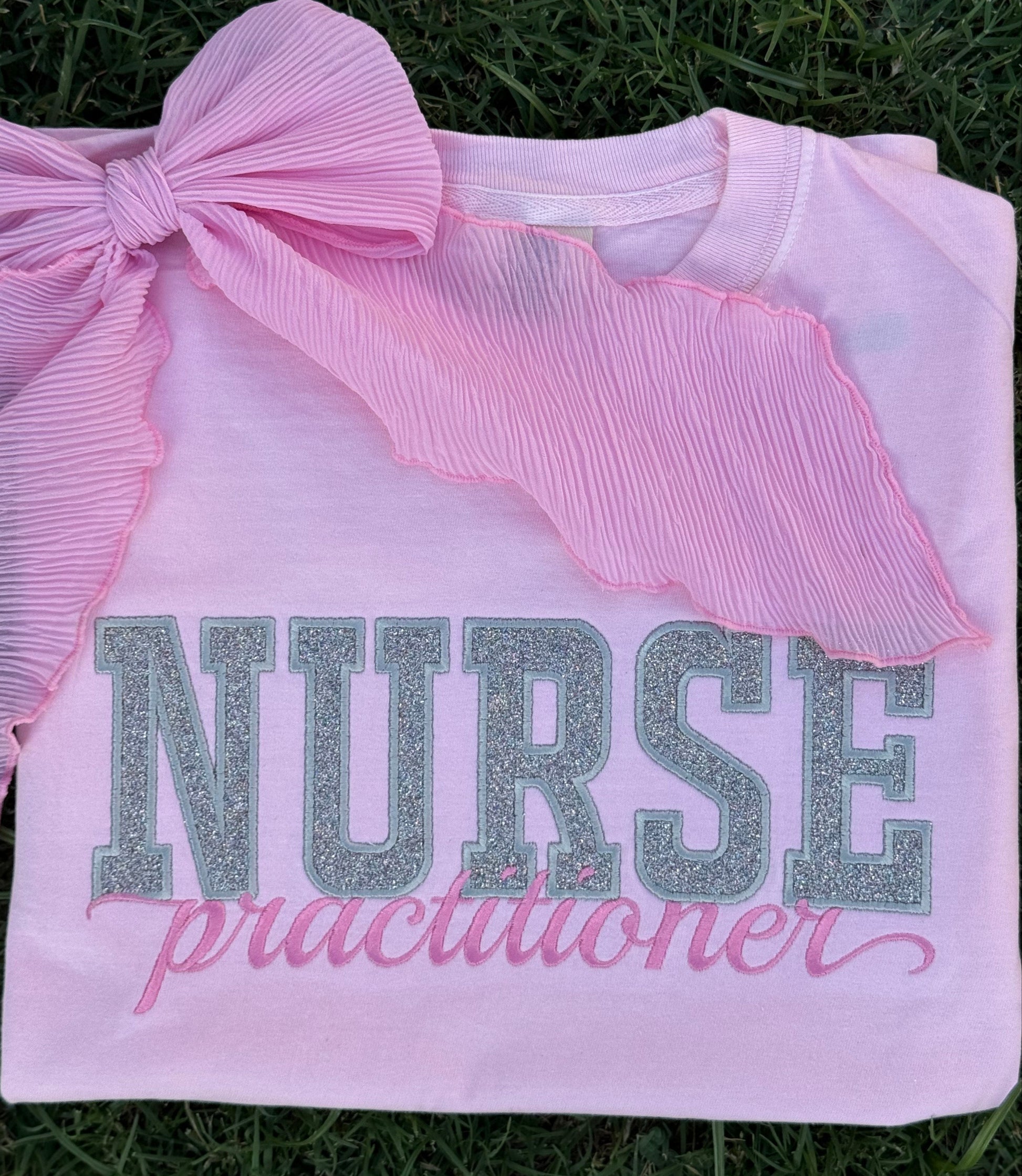 White shirt with pink bow and 'NURSE practitioner'
